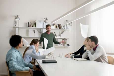 Unsatisfied manager throwing documents with the results of his employees while they're looking in shock.